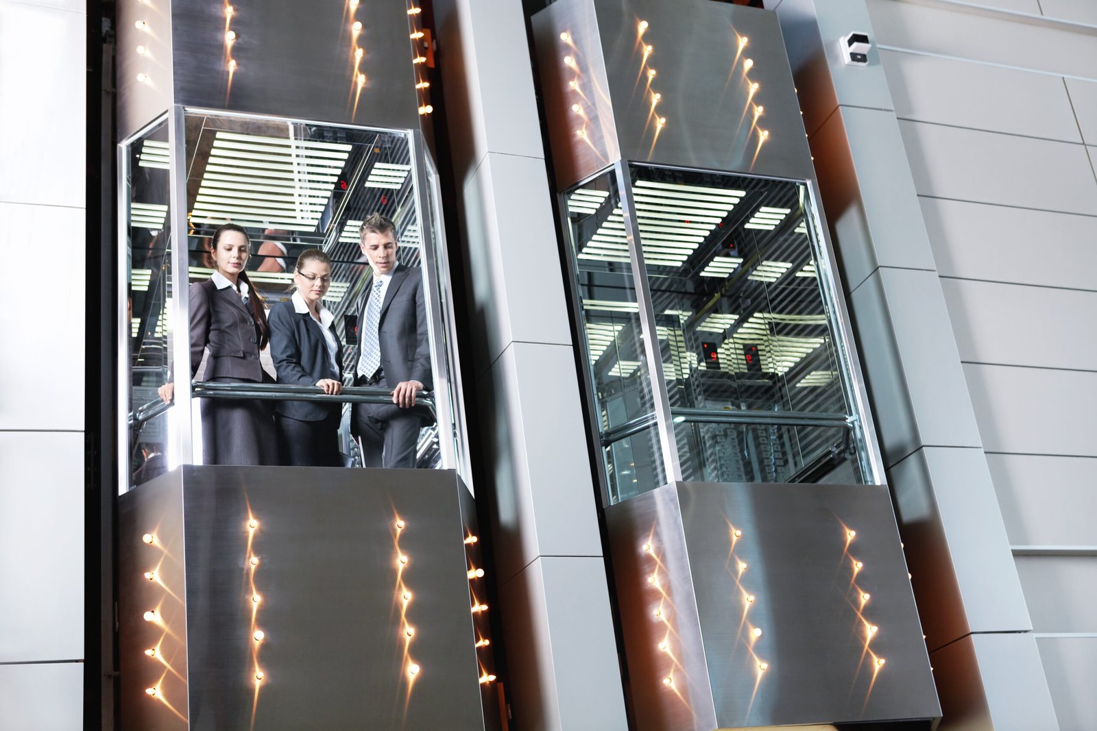 Business professionals riding in a glass-walled elevator representing a project environment similar to JAFITA references