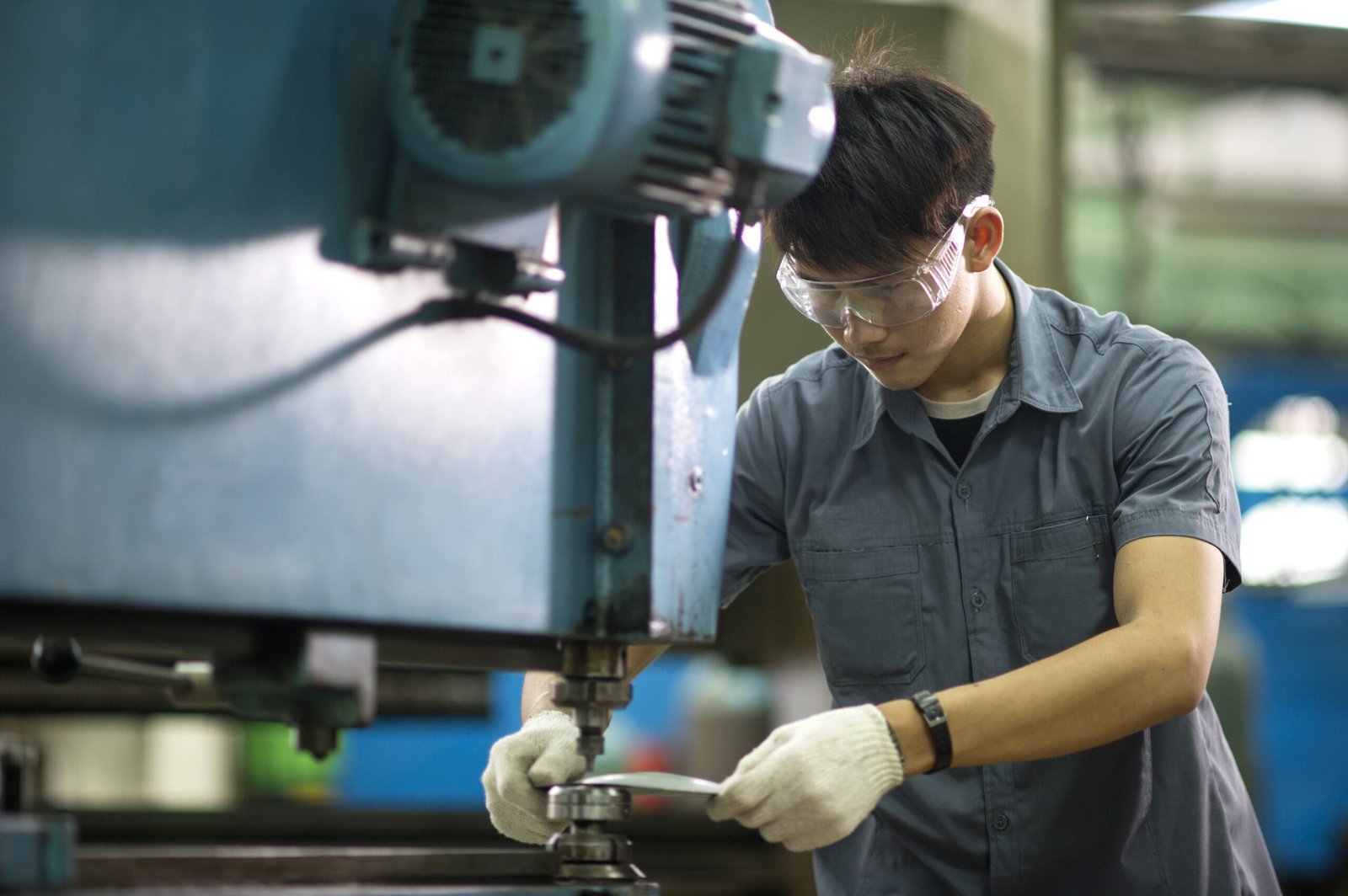 Factory technician operating a machine tool on a metal workpiece