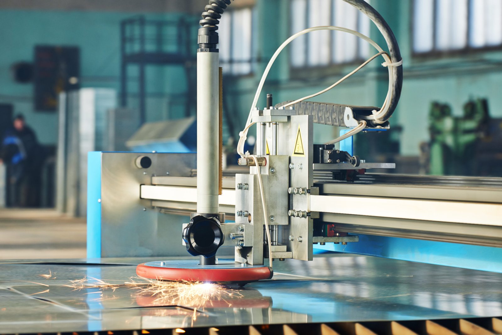 Laser cutting head working across a steel sheet in the workshop