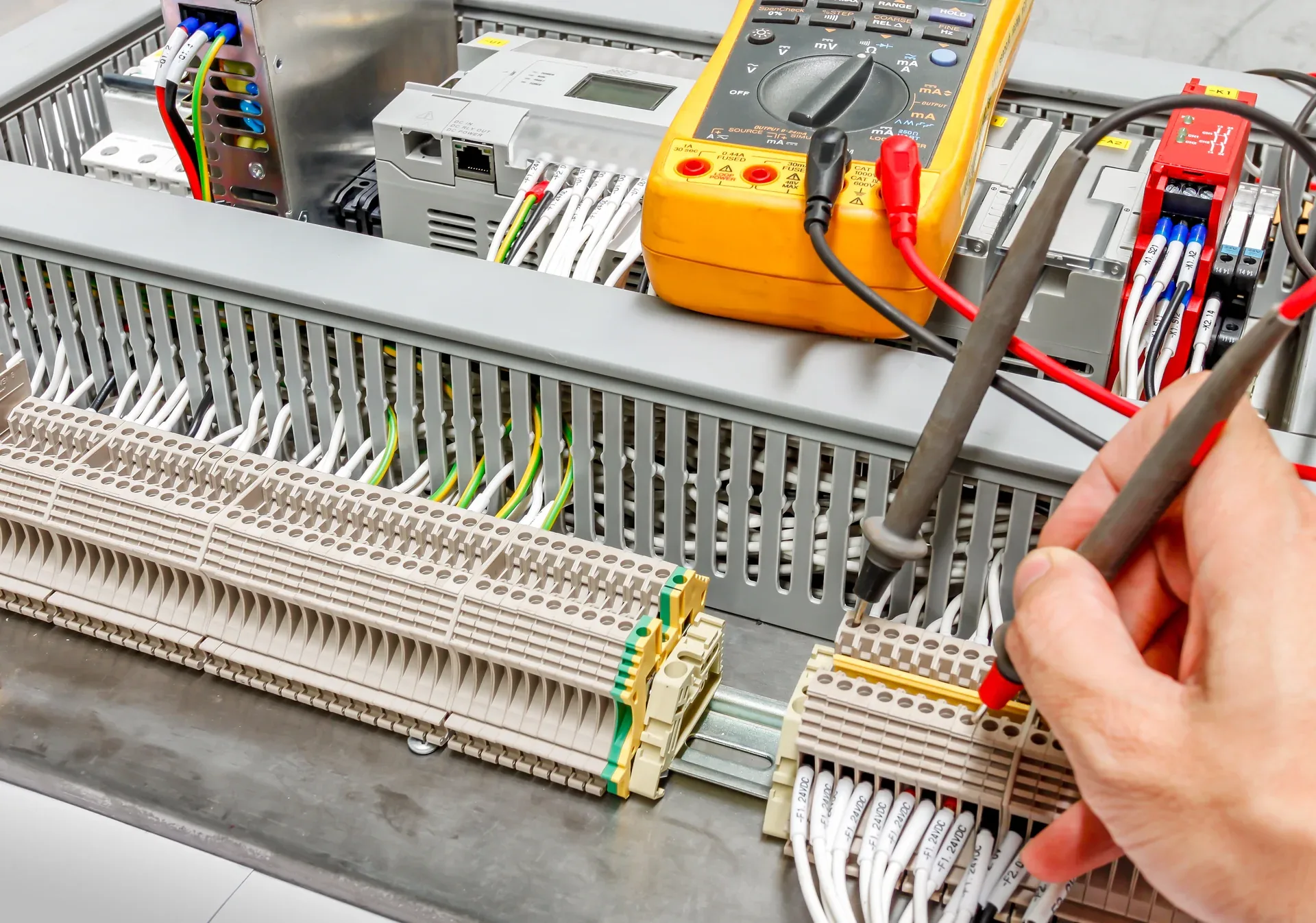 Technician testing electrical control terminals with a multimeter